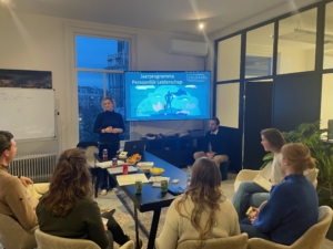 Start van het jaarprogramma Persoonlijk Leiderschap bij Voldaan, met Daniëlle als trainer en jonge professionals in gesprek in een trainingsruimte.